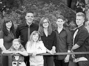 Schwarz-weißes Familienporträt von sechs lächelnden Kindern und Jugendlichen, die gemeinsam an einem Geländer stehen. Ein authentisches Gruppenbild, ideal für Familienfotografie und größere Familien in Erfurt, festgehalten von Michael Schalansky.